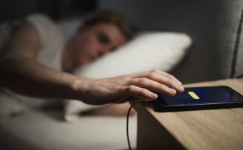 telefono in carica sul comodino mentre un uomo dorme nel letto